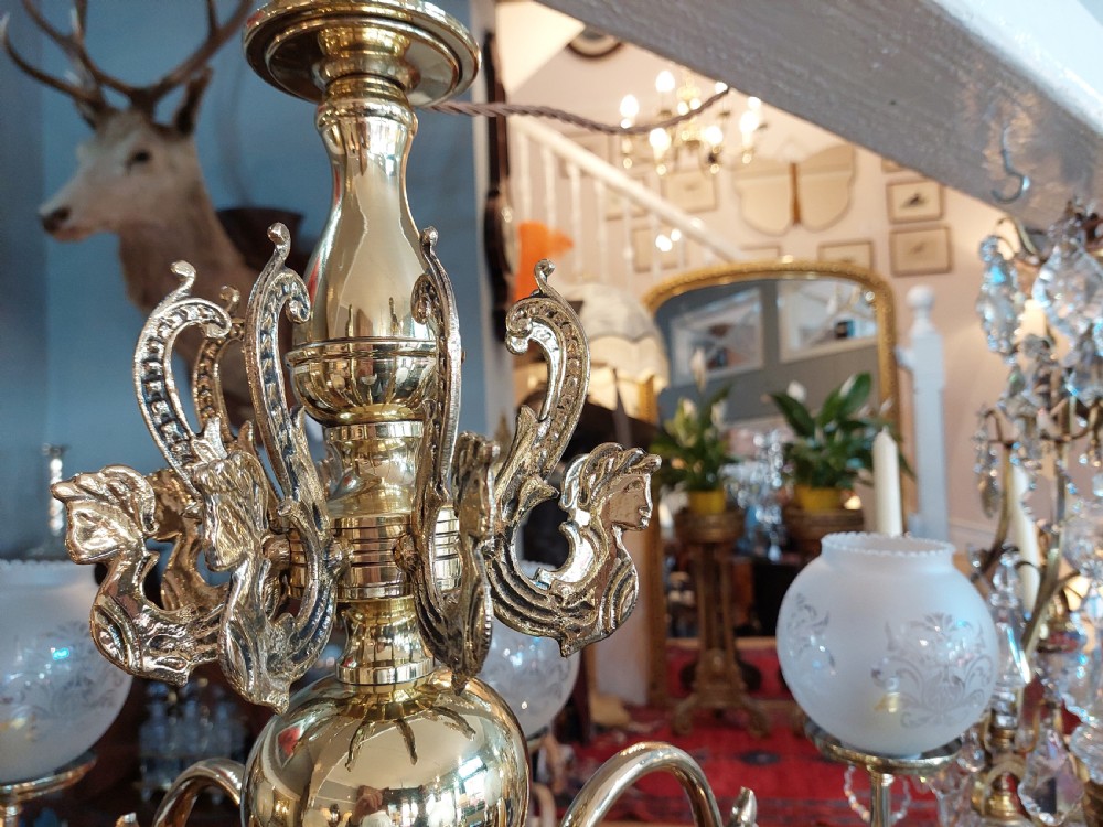 An early twentieth-century polished brass eight-arm chandelier featuring etched frosted glass shades mounted on curved arms around a central baluster stem. View VII