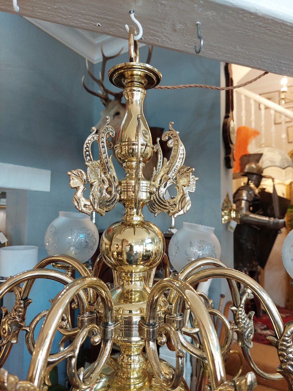 An early twentieth-century polished brass eight-arm chandelier featuring etched frosted glass shades mounted on curved arms around a central baluster stem. View VIII