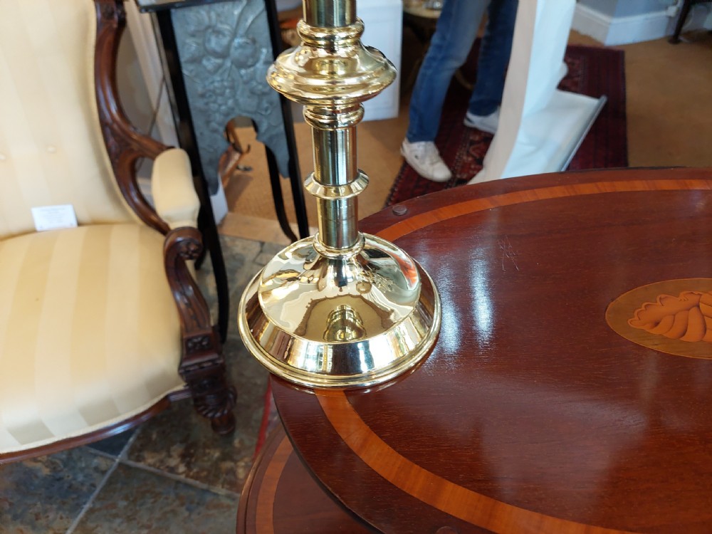 A pair of 19th-century Gothic Revival brass altar candlesticks converted into table lamps with patterned cream fabric shades featuring tassel fringe. View IV