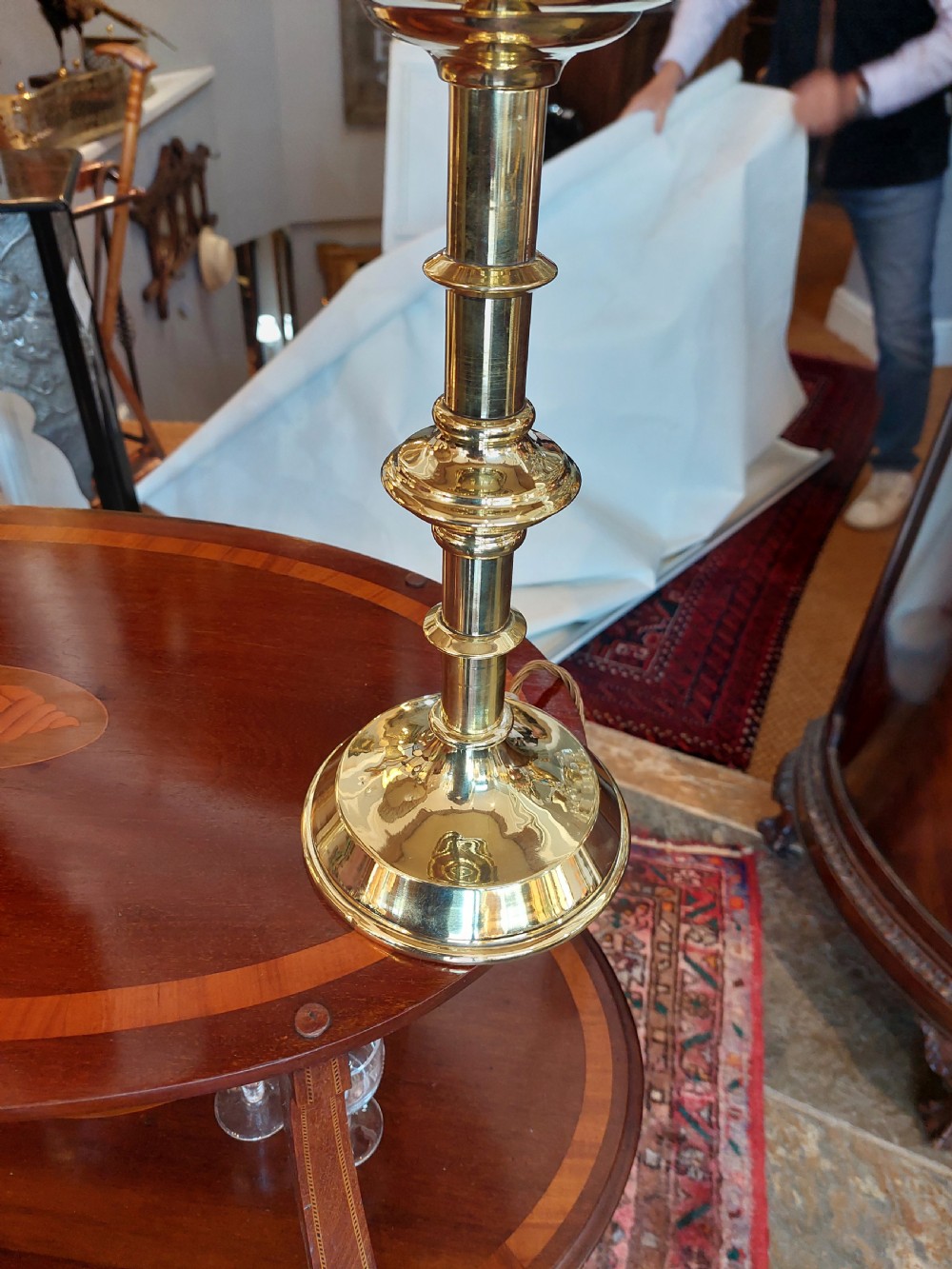 A pair of 19th-century Gothic Revival brass altar candlesticks converted into table lamps with patterned cream fabric shades featuring tassel fringe. View V