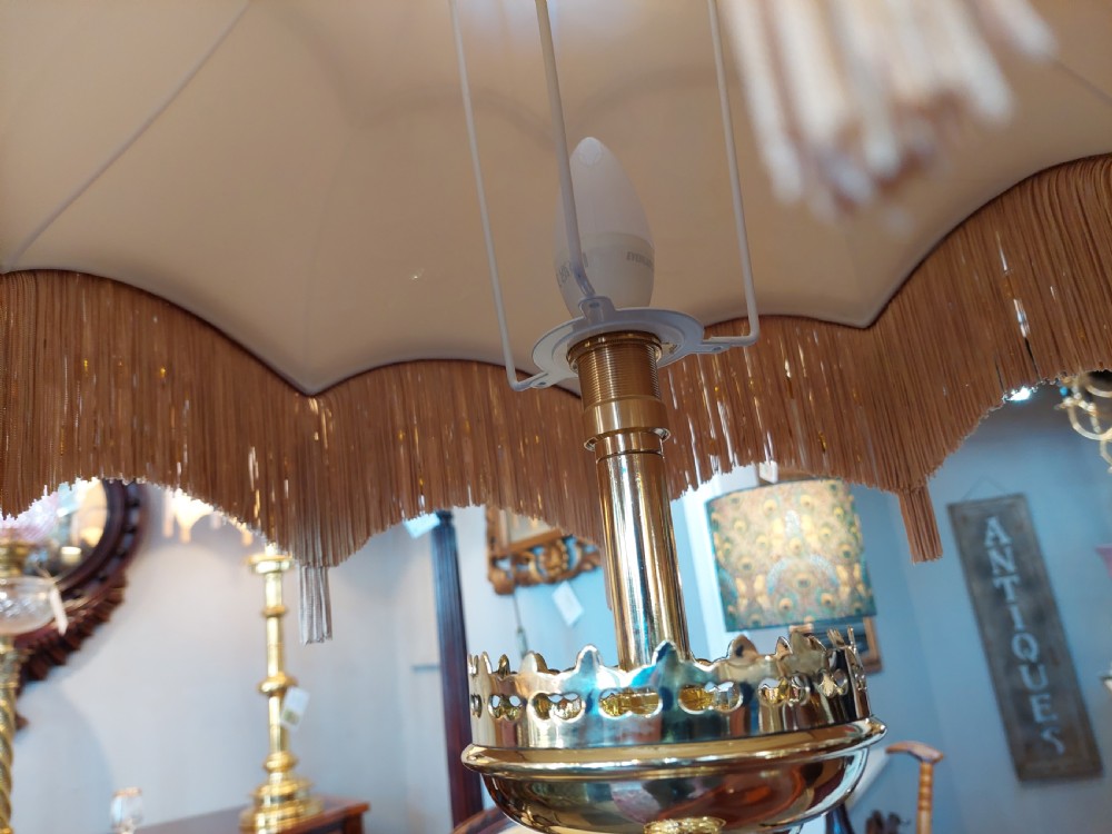 A pair of 19th-century Gothic Revival brass altar candlesticks converted into table lamps with patterned cream fabric shades featuring tassel fringe. View VII