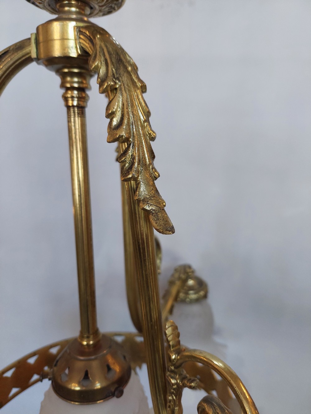 An early 20th-century French cast brass three-light chandelier featuring scrolled arms, a decorative pierced gallery ring, and frosted fluted glass shades. View II