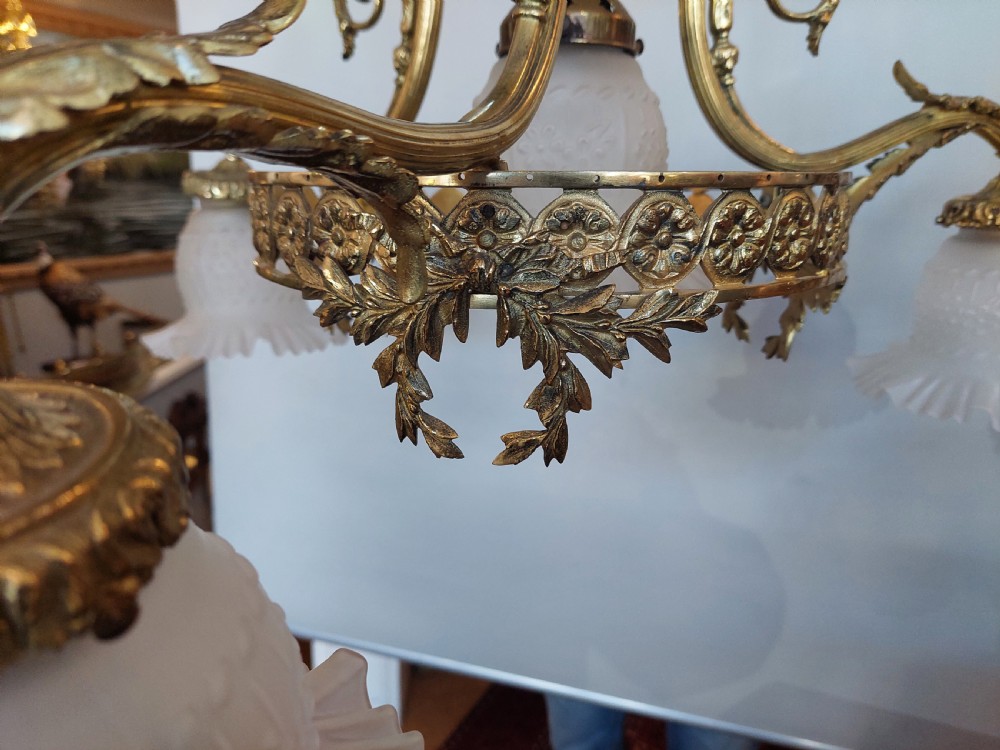 An early 20th-century French cast brass three-light chandelier featuring scrolled arms, a decorative pierced gallery ring, and frosted fluted glass shades. View IV