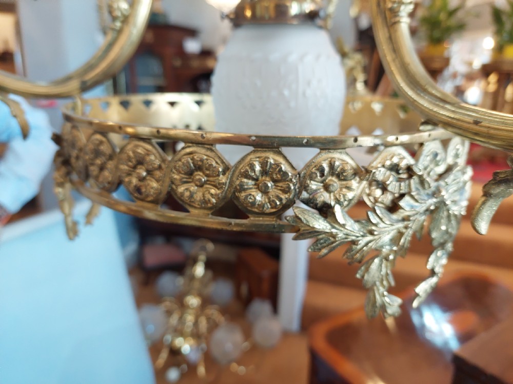 An early 20th-century French cast brass three-light chandelier featuring scrolled arms, a decorative pierced gallery ring, and frosted fluted glass shades. View V