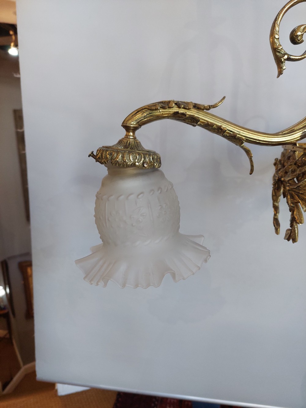 An early 20th-century French cast brass three-light chandelier featuring scrolled arms, a decorative pierced gallery ring, and frosted fluted glass shades. View VI