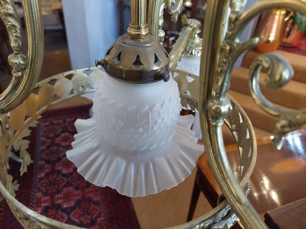 An early 20th-century French cast brass three-light chandelier featuring scrolled arms, a decorative pierced gallery ring, and frosted fluted glass shades. View X