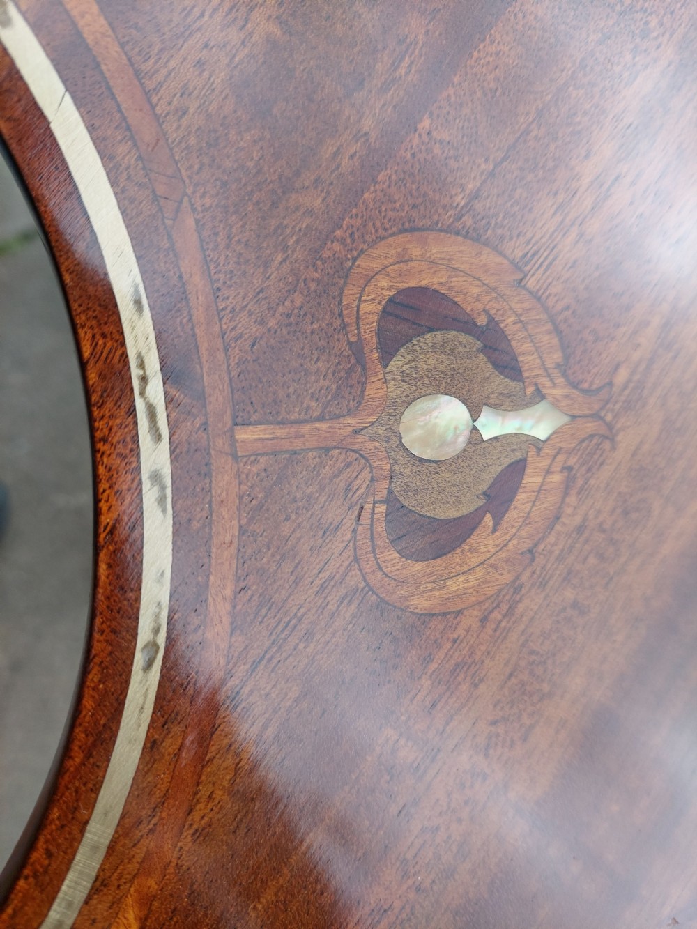 An Edwardian mahogany occasional table featuring a serpentine shaped top with inlaid floral motifs, slender splayed legs, and a central circular lower shelf. View IV