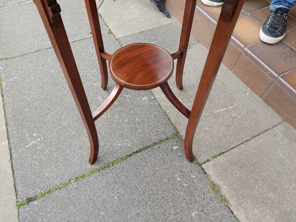 An Edwardian mahogany occasional table featuring a serpentine shaped top with inlaid floral motifs, slender splayed legs, and a central circular lower shelf. View V