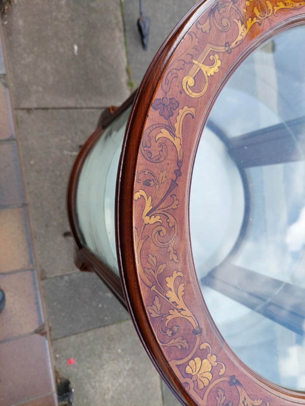 An Edwardian mahogany and marquetry oval bijouterie display table featuring curved glass sides, cabriole legs, and a glazed top. View III