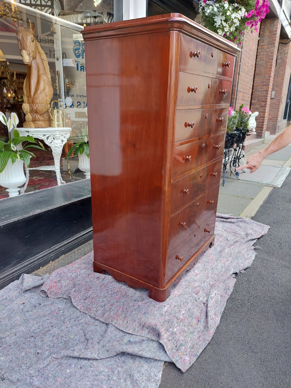 A tall Victorian flame mahogany semainier chest featuring seven stacked drawers with turned wooden handles set on a plinth base. View VII