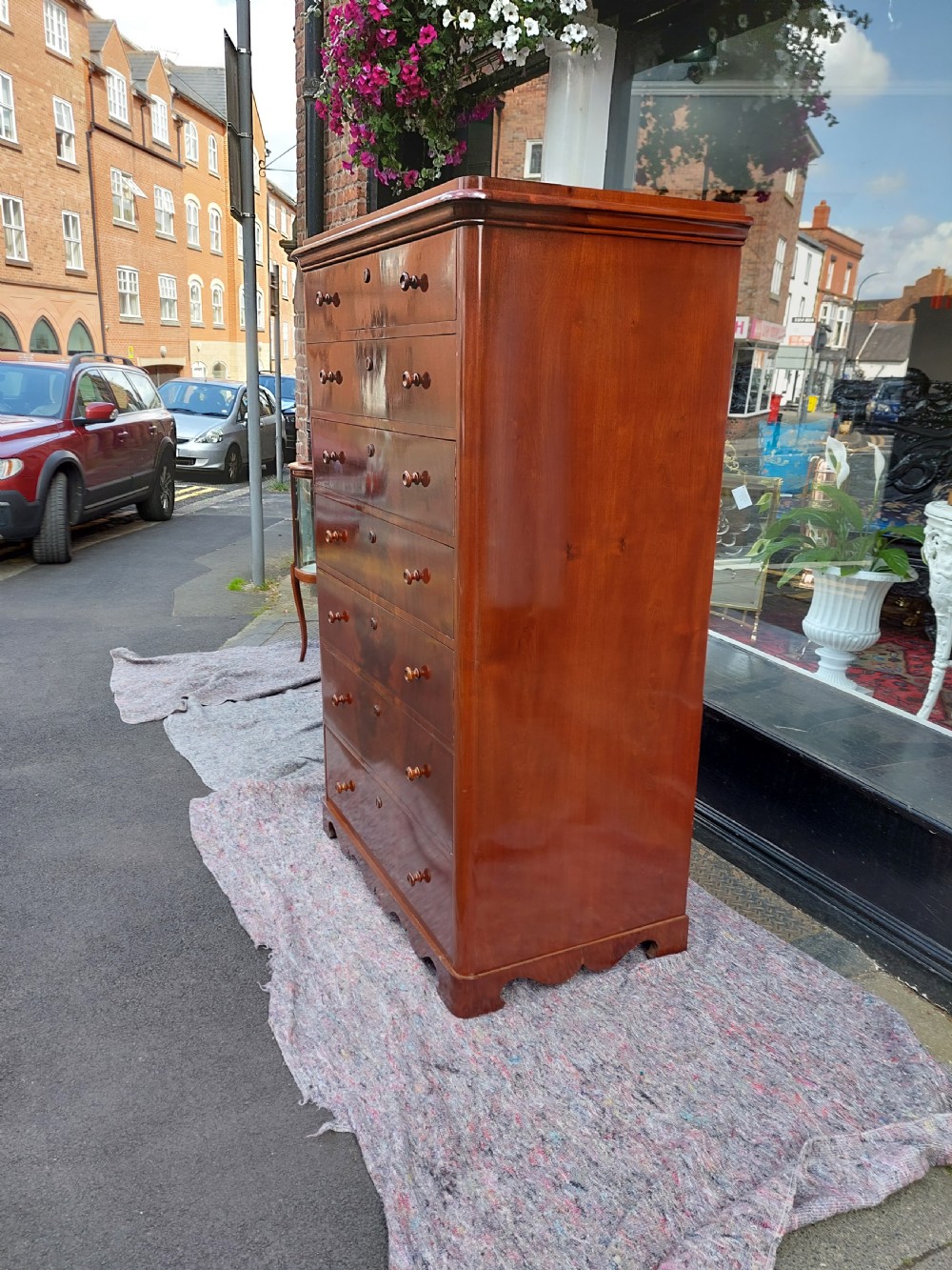 A tall Victorian flame mahogany semainier chest featuring seven stacked drawers with turned wooden handles set on a plinth base. View IX