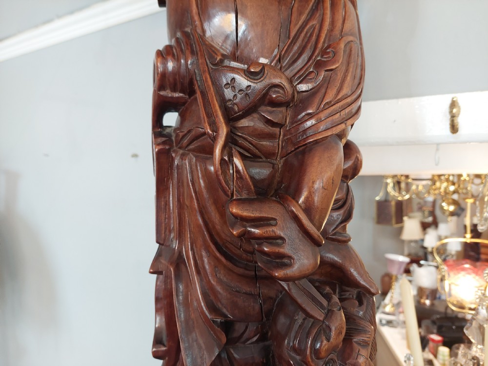 An early 20th-century Chinese carved rootwood table lamp featuring a figural base and a cylindrical shade with cream fringe and red trim. View IV