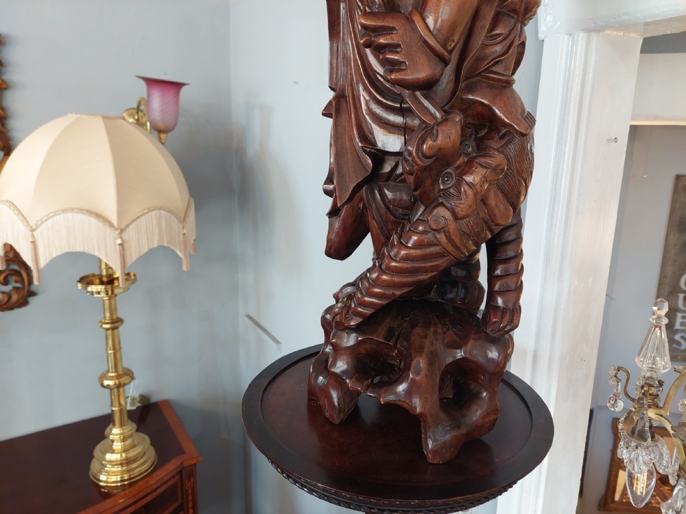 An early 20th-century Chinese carved rootwood table lamp featuring a figural base and a cylindrical shade with cream fringe and red trim. View VII