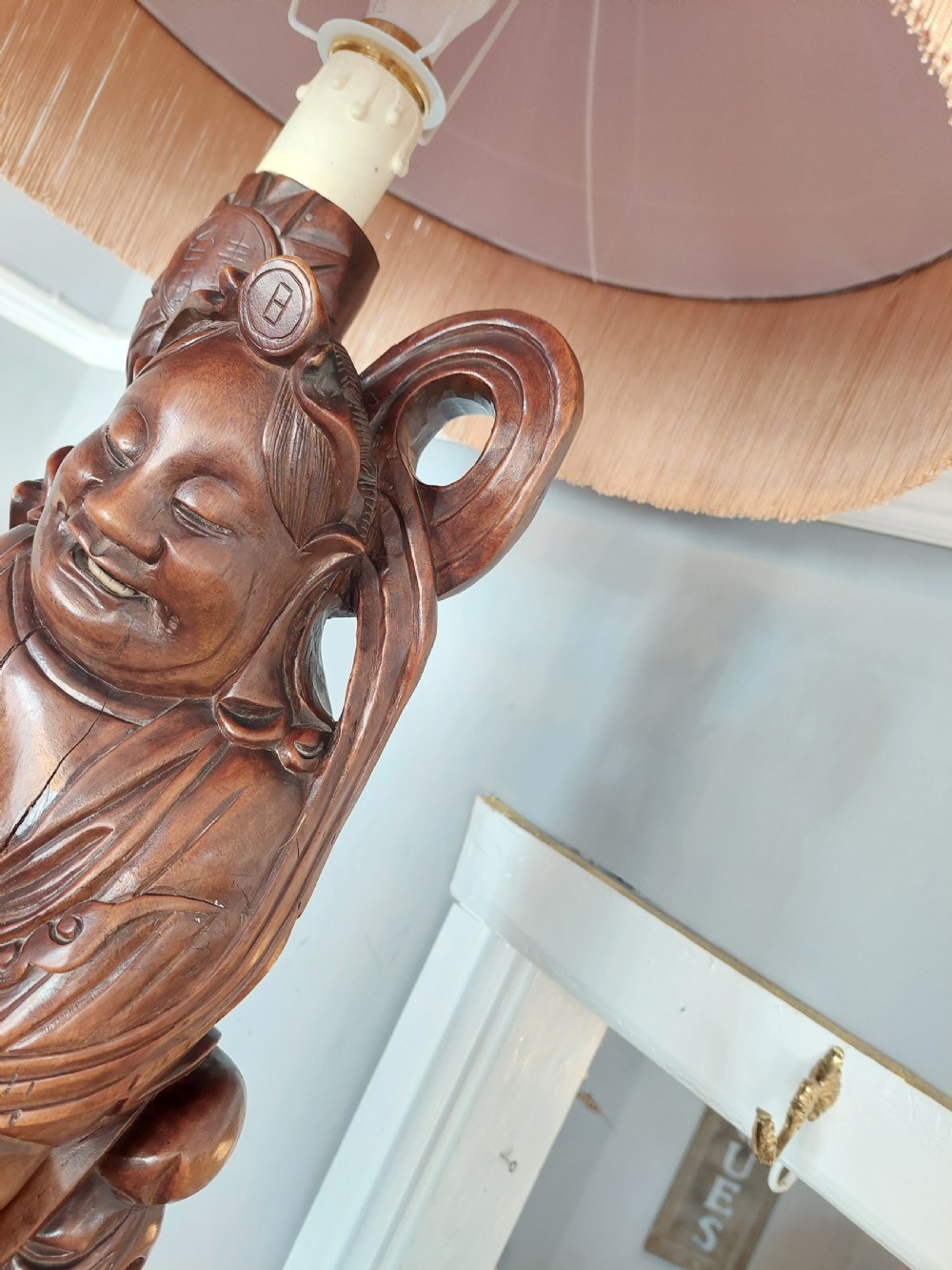 An early 20th-century Chinese carved rootwood table lamp featuring a figural base and a cylindrical shade with cream fringe and red trim. View VIII