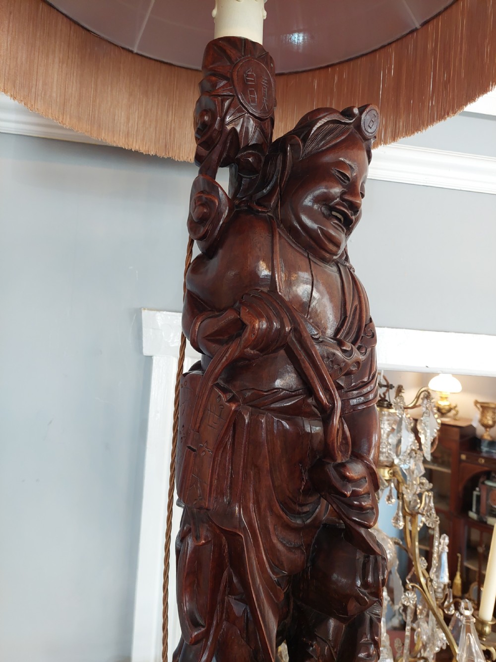An early 20th-century Chinese carved rootwood table lamp featuring a figural base and a cylindrical shade with cream fringe and red trim. View IX