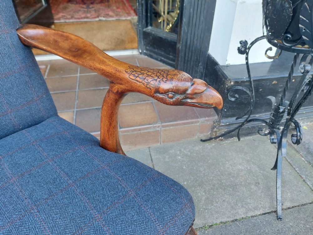 An early twentieth-century Georgian Revival high-backed armchair upholstered in blue fabric with carved walnut legs and eagle head handrests. View V