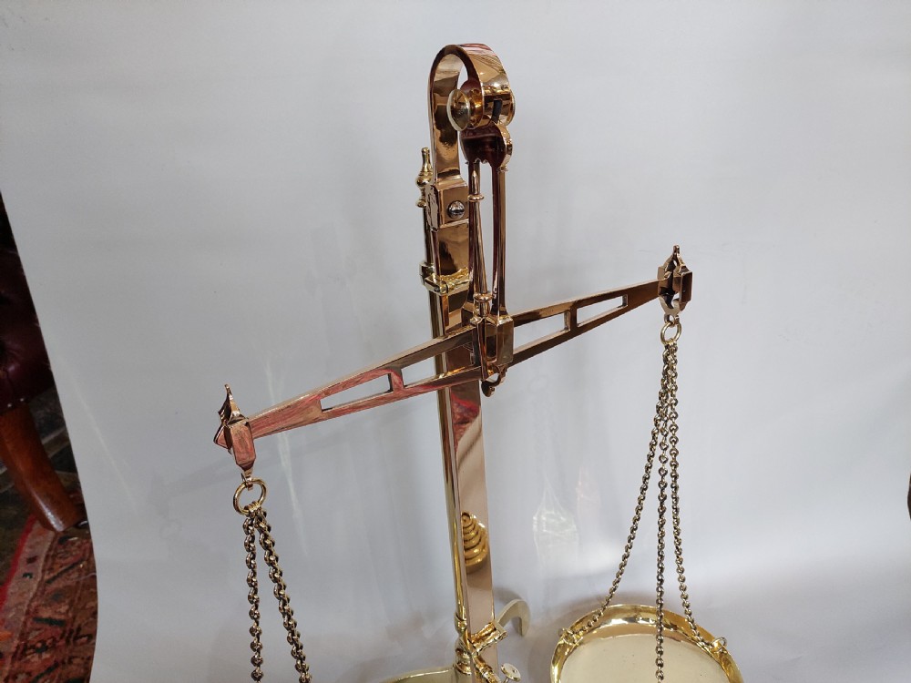 A set of Victorian polished brass beam balance scales with suspended pans and nested weights. View III