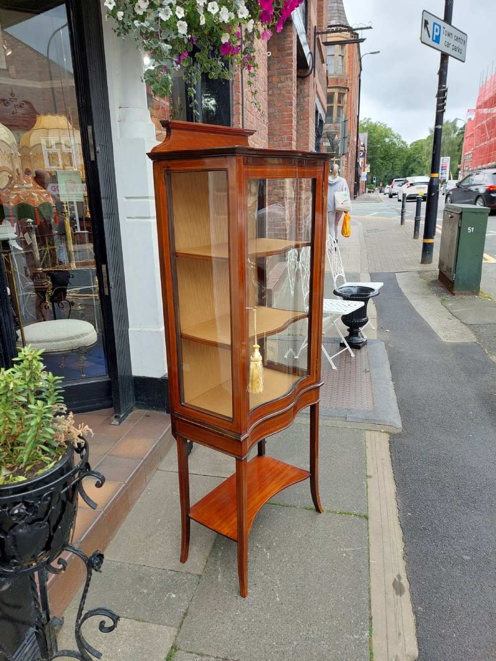 A late Victorian mahogany display cabinet featuring a serpentine glass door, satinwood stringing inlay, slender square tapered legs, and an lower undertier shelf. View VII