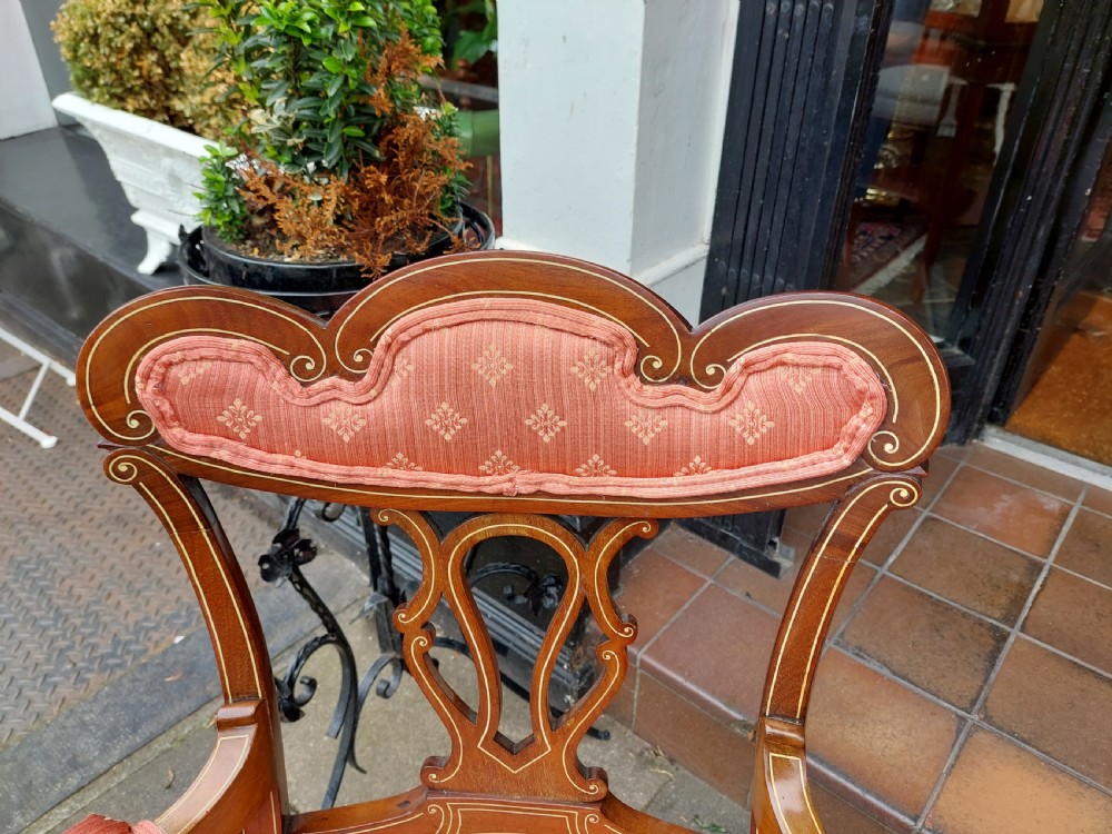 A pair of late Victorian mahogany armchairs featuring inlaid wood detail, padded armrests, and patterned pink fabric upholstery. View II
