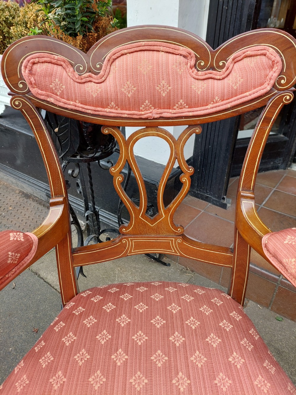A pair of late Victorian mahogany armchairs featuring inlaid wood detail, padded armrests, and patterned pink fabric upholstery. View III