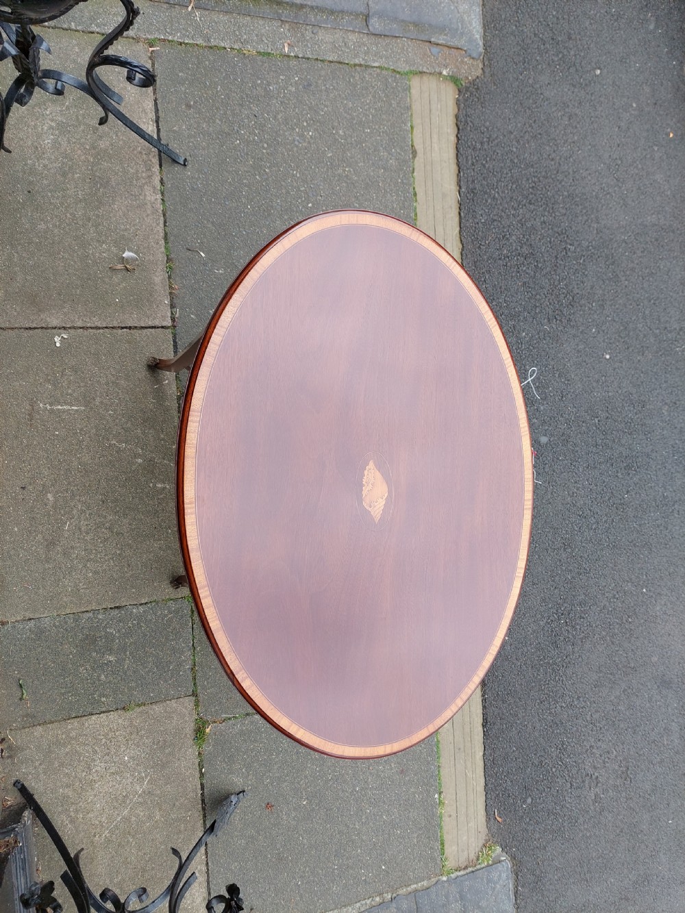 An oval Edwardian mahogany occasional table featuring satinwood crossbanding, a central inlaid motif, an oval undertier, and splayed tapered legs. View II