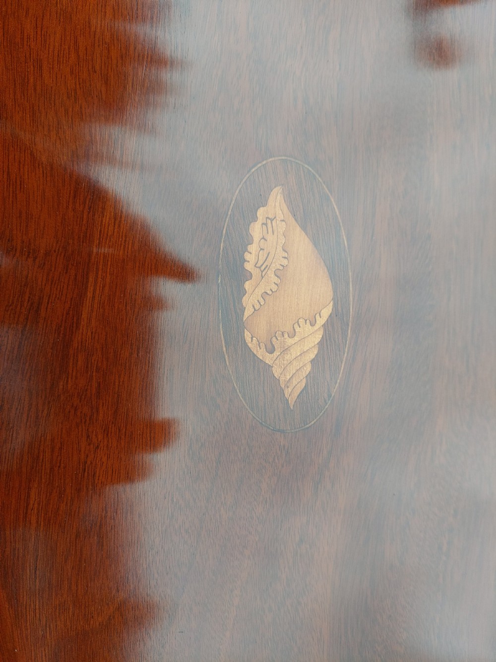 An oval Edwardian mahogany occasional table featuring satinwood crossbanding, a central inlaid motif, an oval undertier, and splayed tapered legs. View III