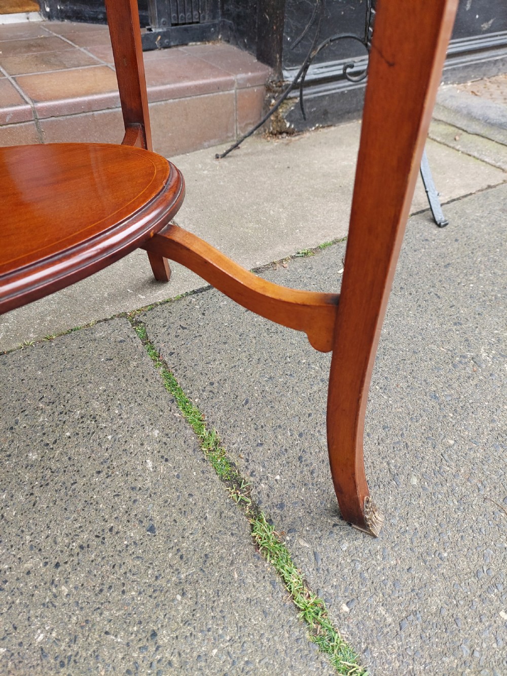 An oval Edwardian mahogany occasional table featuring satinwood crossbanding, a central inlaid motif, an oval undertier, and splayed tapered legs. View VIII