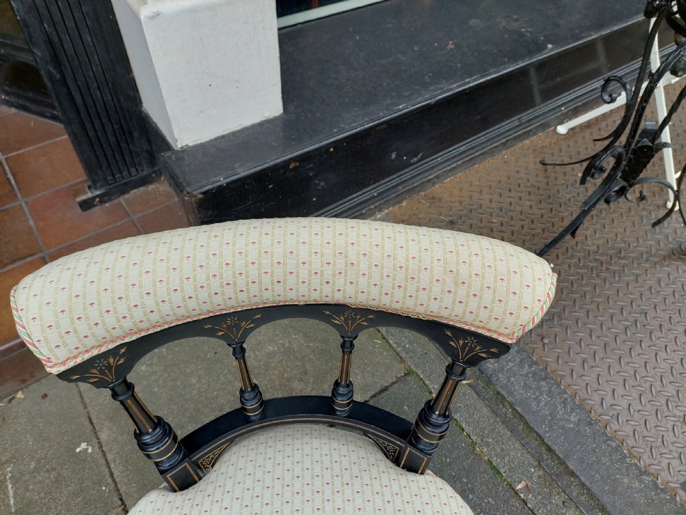A pair of small Victorian ebonised chairs with cream patterned upholstery, turned spindles, gilt accents, and brass castors. View III