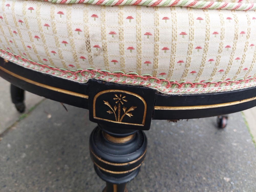 A pair of small Victorian ebonised chairs with cream patterned upholstery, turned spindles, gilt accents, and brass castors. View VI