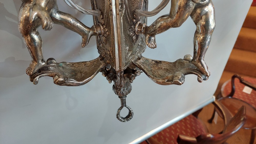 A mid-19th-century silver-plated ceiling light fitting decorated with sculpted cherub figures supporting candle sconces. View III