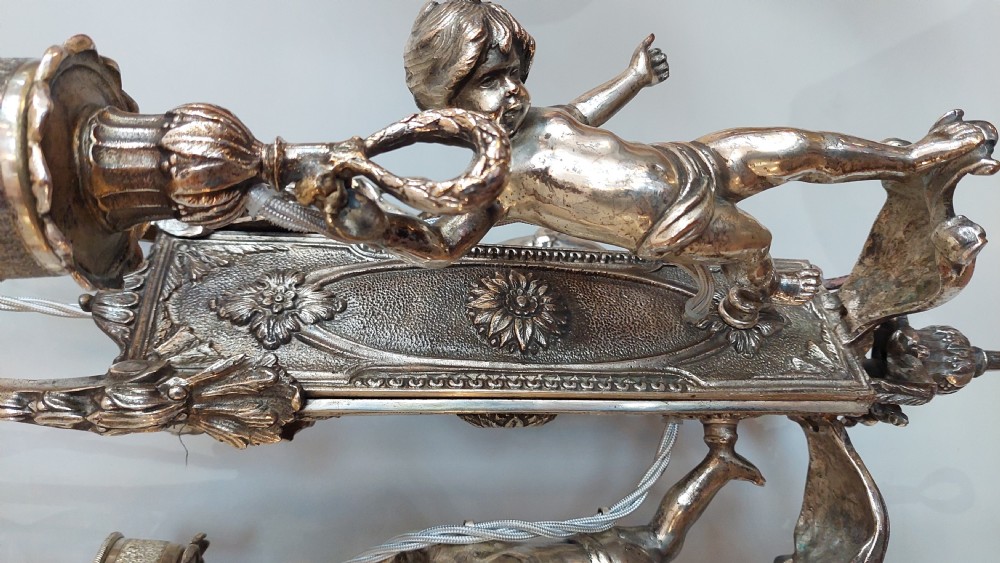 A mid-19th-century silver-plated ceiling light fitting decorated with sculpted cherub figures supporting candle sconces. View IV
