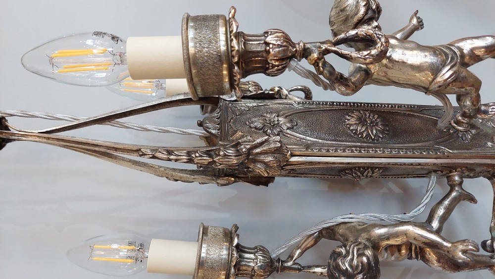 A mid-19th-century silver-plated ceiling light fitting decorated with sculpted cherub figures supporting candle sconces. View V