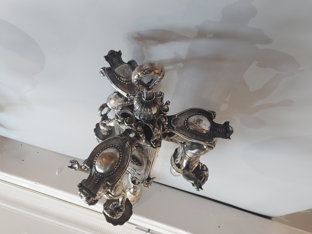 A mid-19th-century silver-plated ceiling light fitting decorated with sculpted cherub figures supporting candle sconces. View IX
