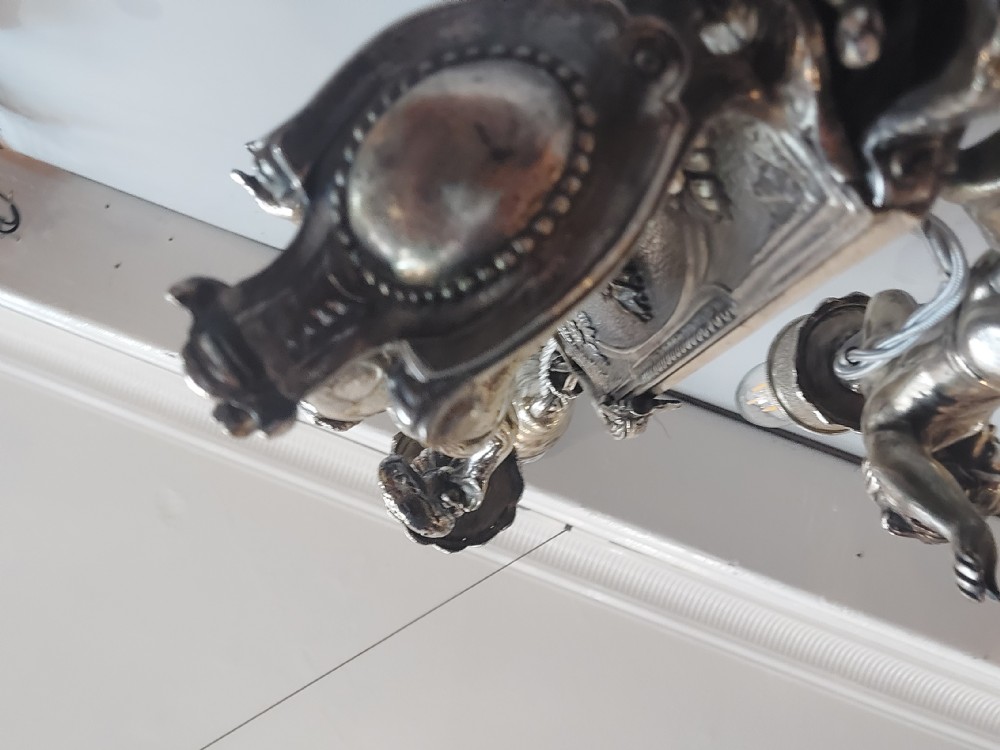 A mid-19th-century silver-plated ceiling light fitting decorated with sculpted cherub figures supporting candle sconces. View X
