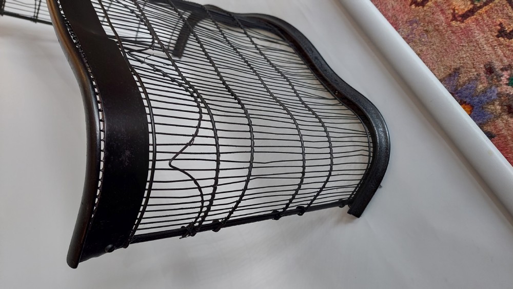 A black painted Edwardian wire mesh nursery fender with a high curved metal frame and vertical wire weaving. View II