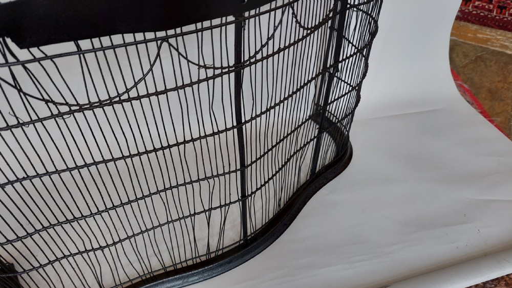 A black painted Edwardian wire mesh nursery fender with a high curved metal frame and vertical wire weaving. View III