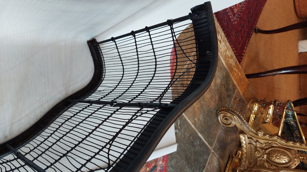 A black painted Edwardian wire mesh nursery fender with a high curved metal frame and vertical wire weaving. View V