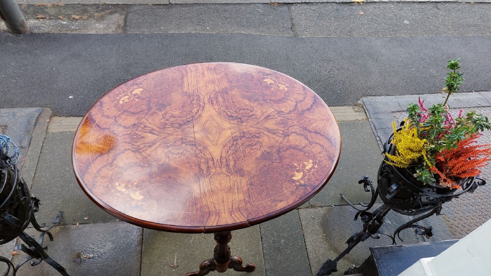 A Victorian burr walnut Sutherland table featuring floral marquetry inlay, twin turned column supports, and carved splayed legs fitted with ceramic castors. View V