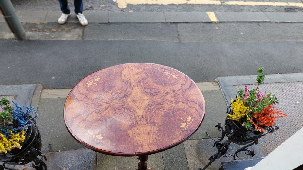 A Victorian burr walnut Sutherland table featuring floral marquetry inlay, twin turned column supports, and carved splayed legs fitted with ceramic castors. View VI
