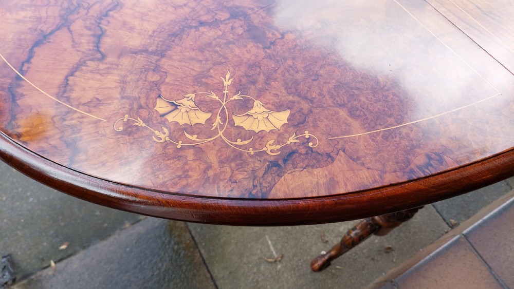 A Victorian burr walnut Sutherland table featuring floral marquetry inlay, twin turned column supports, and carved splayed legs fitted with ceramic castors. View VII