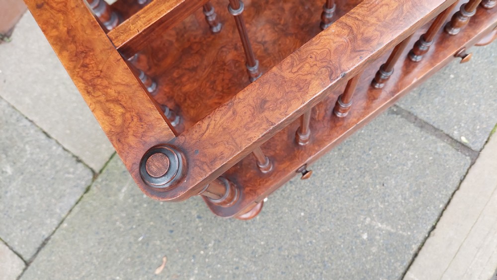 A Victorian walnut Canterbury featuring multiple open compartments formed by turned spindles, sitting above a single drawer with wooden knobs and turned legs on castors. View VII