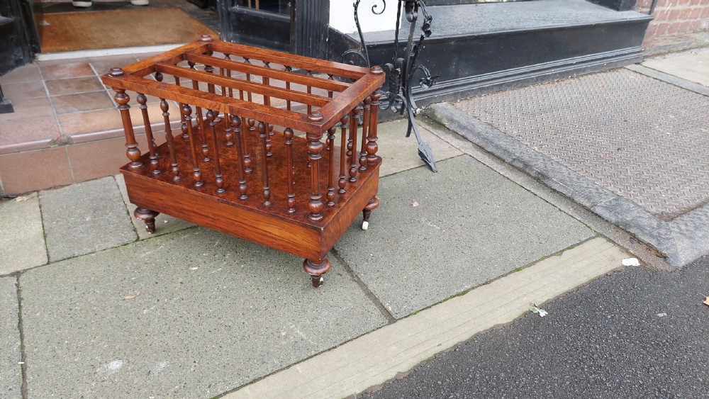 A Victorian walnut Canterbury featuring multiple open compartments formed by turned spindles, sitting above a single drawer with wooden knobs and turned legs on castors. View VIII