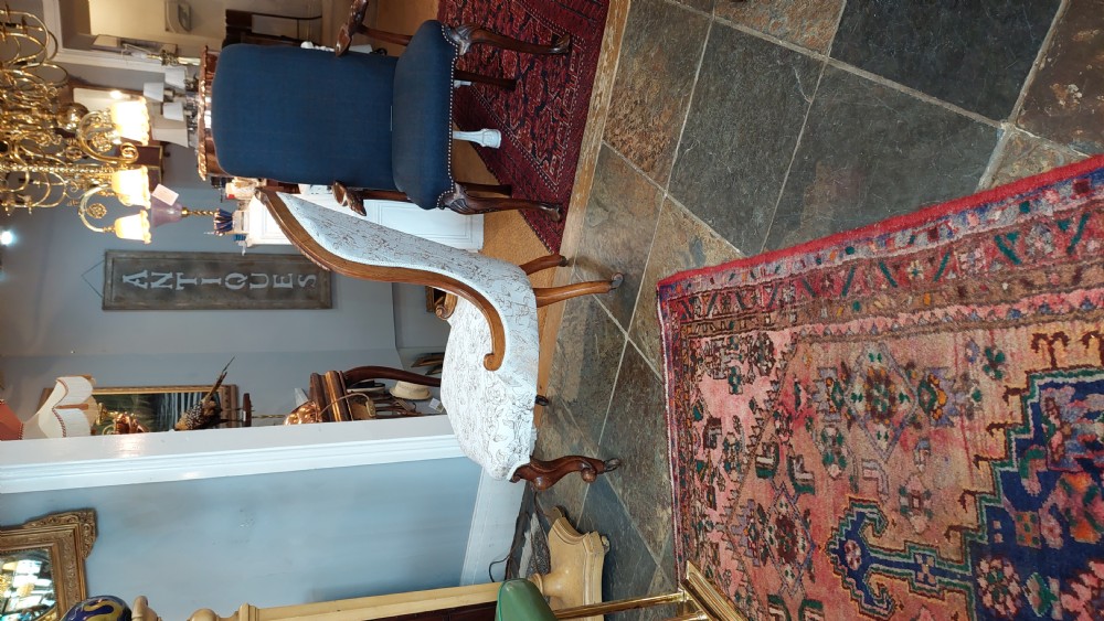 A Victorian low-seated nursing chair crafted from carved walnut featuring floral patterned cream fabric, spoon back, cabriole legs, and castors. View VII