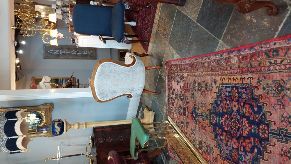 A Victorian low-seated nursing chair crafted from carved walnut featuring floral patterned cream fabric, spoon back, cabriole legs, and castors. View VIII