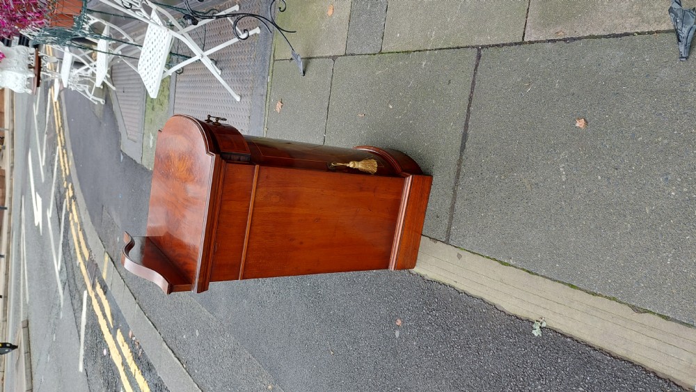 An Edwardian mahogany bedside cabinet featuring a curved front, single upper drawer, inlaid oval panel door, and shaped gallery top. View IX