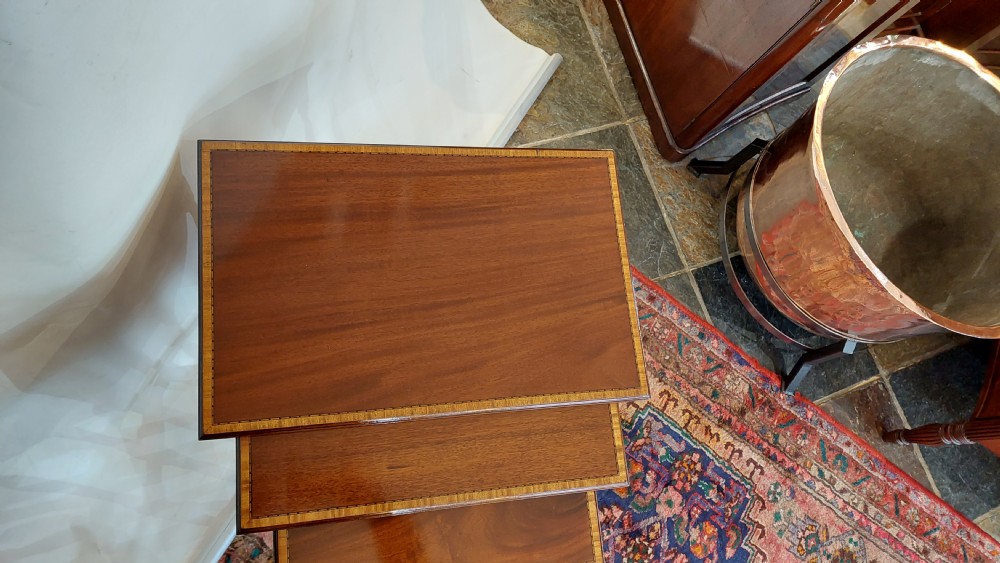A set of three graduated Edwardian mahogany nesting tables featuring slender turned legs, cross-stretchers, and inset glass tops. View II