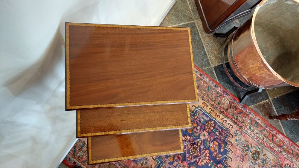 A set of three graduated Edwardian mahogany nesting tables featuring slender turned legs, cross-stretchers, and inset glass tops. View III
