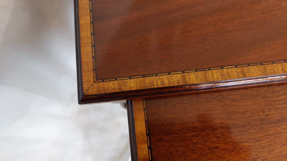 A set of three graduated Edwardian mahogany nesting tables featuring slender turned legs, cross-stretchers, and inset glass tops. View IV