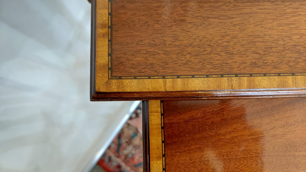 A set of three graduated Edwardian mahogany nesting tables featuring slender turned legs, cross-stretchers, and inset glass tops. View V
