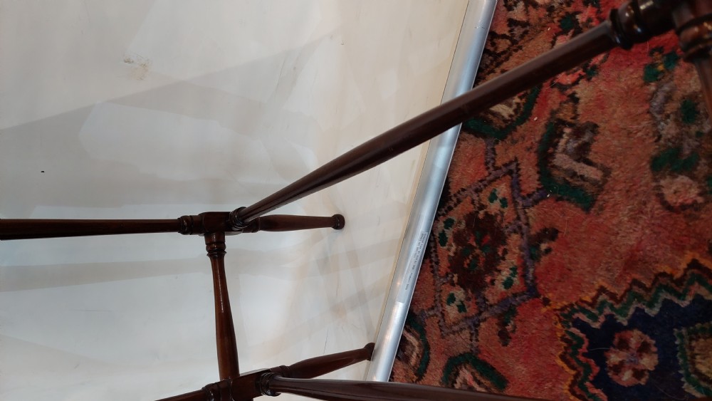 A set of three graduated Edwardian mahogany nesting tables featuring slender turned legs, cross-stretchers, and inset glass tops. View VII